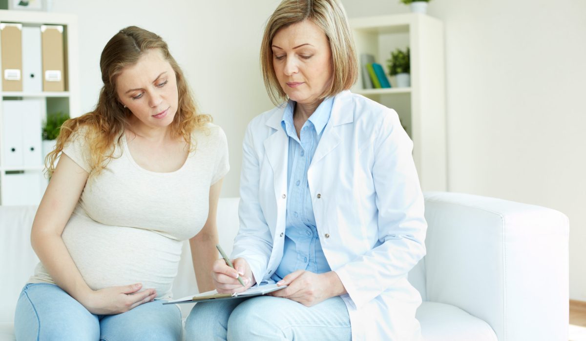 Young pregnant woman listening to prescription of doctor after regular examination at hospital